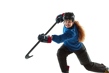 Image showing Young female hockey player with the stick on ice court and white background