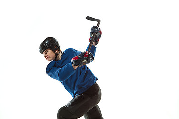 Image showing Young female hockey player with the stick on ice court and white background