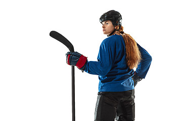 Image showing Young female hockey player with the stick on ice court and white background