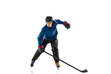 Image showing Young female hockey player with the stick on ice court and white background