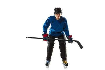 Image showing Young female hockey player with the stick on ice court and white background