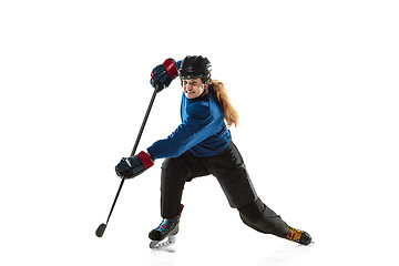 Image showing Young female hockey player with the stick on ice court and white background