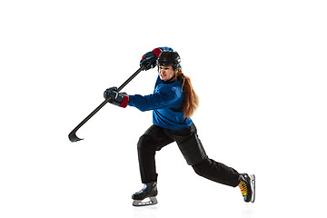 Image showing Young female hockey player with the stick on ice court and white background