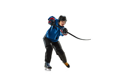 Image showing Young female hockey player with the stick on ice court and white background