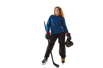 Image showing Young female hockey player with the stick on ice court and white background