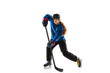 Image showing Young female hockey player with the stick on ice court and white background