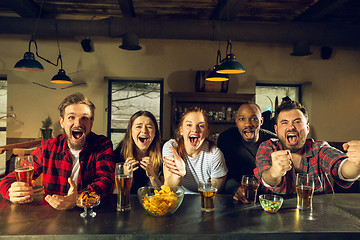 Image showing Sport fans cheering at bar, pub and drinking beer while championship, competition is going