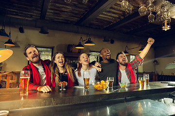 Image showing Sport fans cheering at bar, pub and drinking beer while championship, competition is going