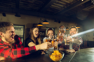 Image showing Sport fans cheering at bar, pub and drinking beer while championship, competition is going