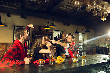 Image showing Sport fans cheering at bar, pub and drinking beer while championship, competition is going