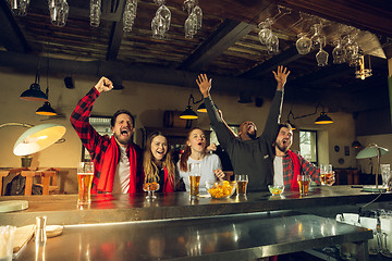 Image showing Sport fans cheering at bar, pub and drinking beer while championship, competition is going