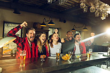 Image showing Sport fans cheering at bar, pub and drinking beer while championship, competition is going