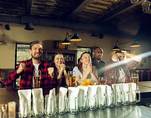 Image showing Sport fans cheering at bar, pub and drinking beer while championship, competition is going