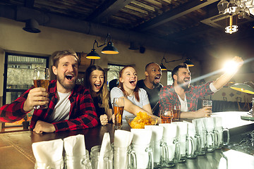 Image showing Sport fans cheering at bar, pub and drinking beer while championship, competition is going