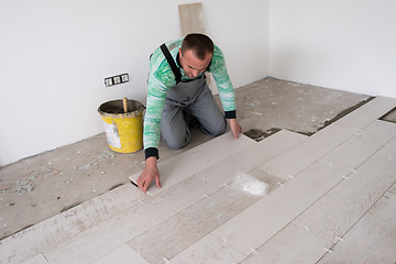 Image showing worker installing the ceramic wood effect tiles on the floor