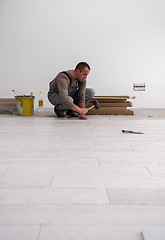 Image showing worker installing the ceramic wood effect tiles on the floor