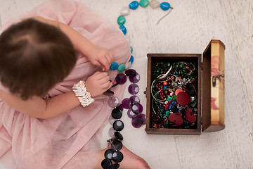 Image showing little girl enjoying while playing with mother\'s jewelry