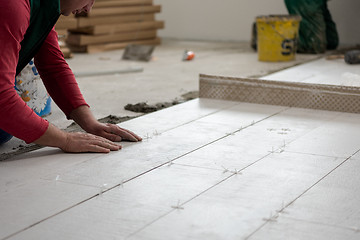 Image showing worker installing the ceramic wood effect tiles on the floor