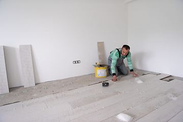 Image showing worker installing the ceramic wood effect tiles on the floor