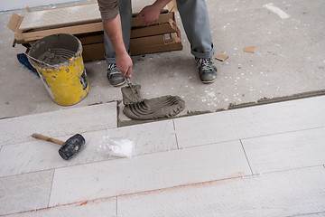 Image showing worker installing the ceramic wood effect tiles on the floor