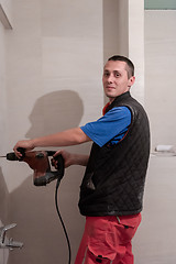 Image showing construction worker drilling holes in the bathroom