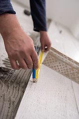 Image showing worker installing the ceramic wood effect tiles on the floor