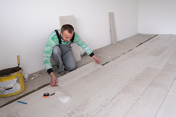 Image showing worker installing the ceramic wood effect tiles on the floor