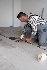 Image showing worker installing the ceramic wood effect tiles on the floor