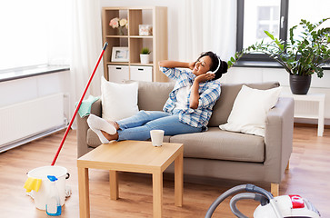 Image showing woman in headphones resting after home cleaning