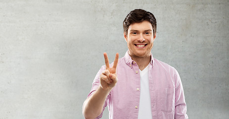 Image showing happy man showing two fingers or peace hand sign