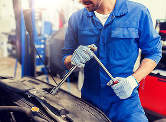 Image showing mechanic man with wrench repairing car at workshop