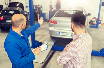 Image showing auto mechanic with clipboard and man at car shop