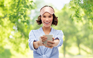 Image showing woman in pajama and sleeping mask drinking coffee