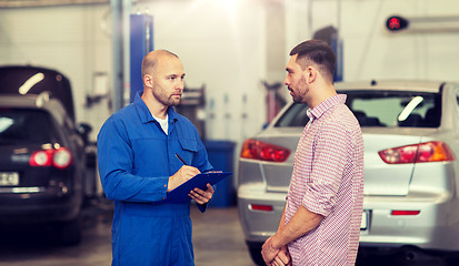 Image showing auto mechanic with clipboard and man at car shop