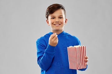 Image showing happy smiling boy in blue hoodie eating popcorn