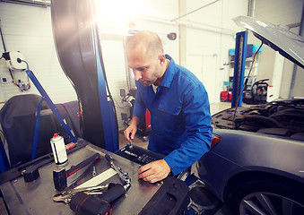 Image showing mechanic man with wrench repairing car at workshop