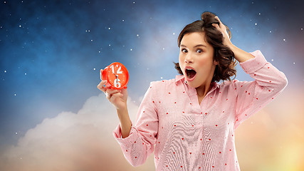 Image showing shocked young woman in pajama with alarm clock