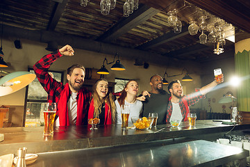 Image showing Sport fans cheering at bar, pub and drinking beer while championship, competition is going