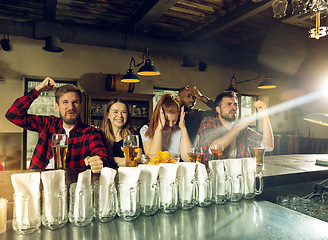 Image showing Sport fans cheering at bar, pub and drinking beer while championship, competition is going