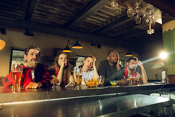 Image showing Sport fans cheering at bar, pub and drinking beer while championship, competition is going