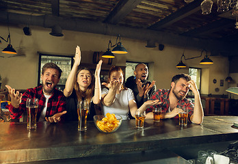 Image showing Sport fans cheering at bar, pub and drinking beer while championship, competition is going