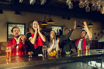 Image showing Sport fans cheering at bar, pub and drinking beer while championship, competition is going