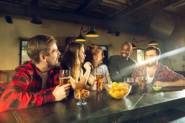 Image showing Sport fans cheering at bar, pub and drinking beer while championship, competition is going