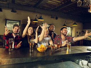 Image showing Sport fans cheering at bar, pub and drinking beer while championship, competition is going