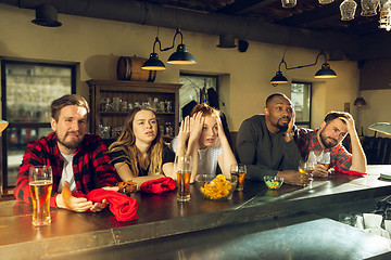 Image showing Sport fans cheering at bar, pub and drinking beer while championship, competition is going