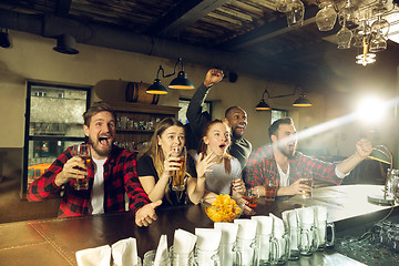 Image showing Sport fans cheering at bar, pub and drinking beer while championship, competition is going