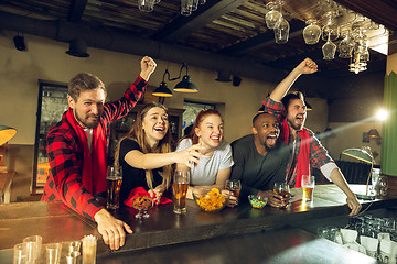 Image showing Sport fans cheering at bar, pub and drinking beer while championship, competition is going