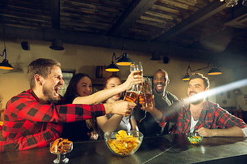 Image showing Sport fans cheering at bar, pub and drinking beer while championship, competition is going