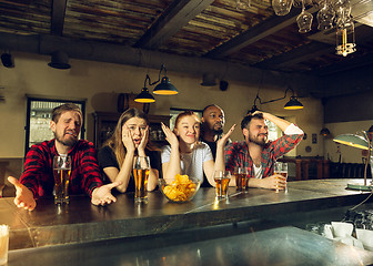 Image showing Sport fans cheering at bar, pub and drinking beer while championship, competition is going