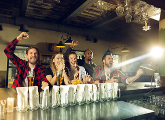 Image showing Sport fans cheering at bar, pub and drinking beer while championship, competition is going